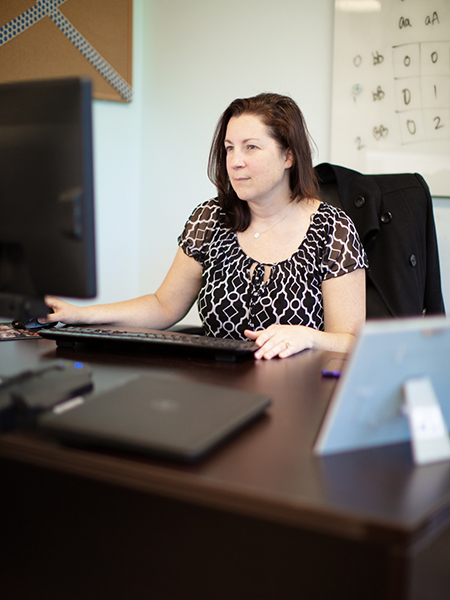 A professional-looking person sitting at a desk while typing on a computer